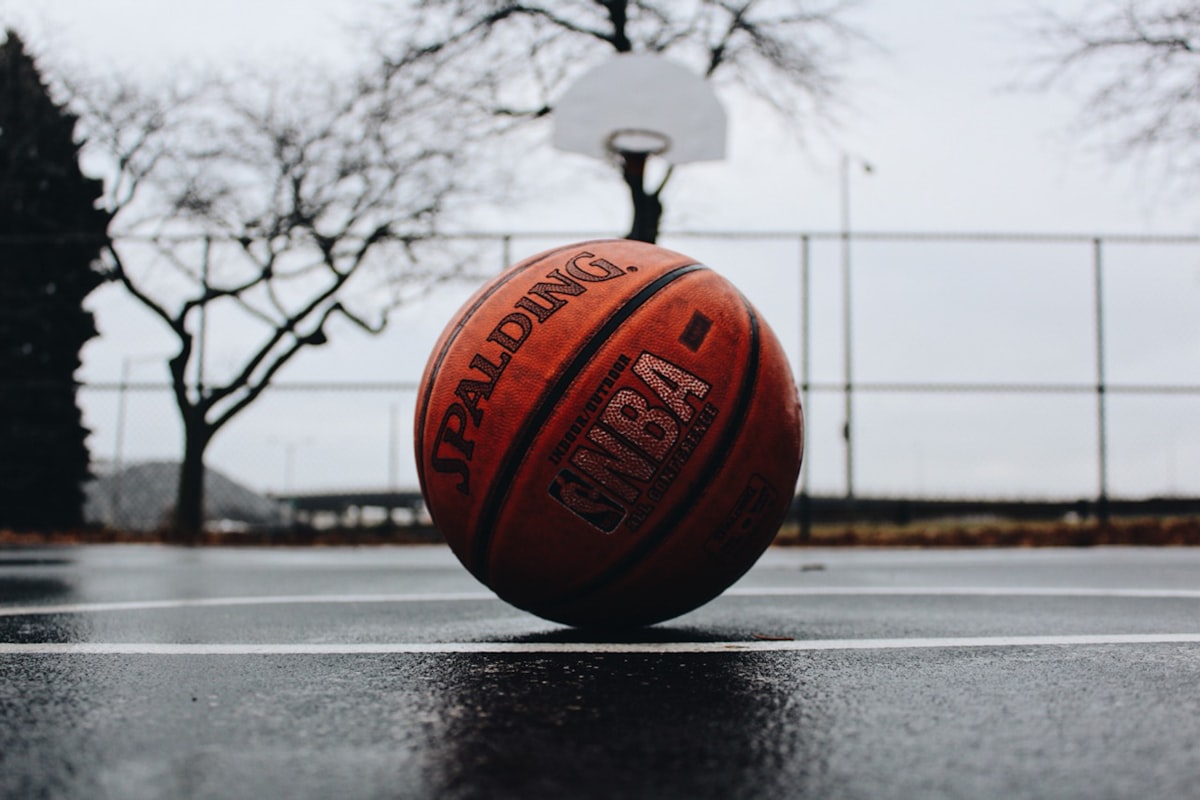 一顆 Spalding 籃球放在雨後的室外球場上