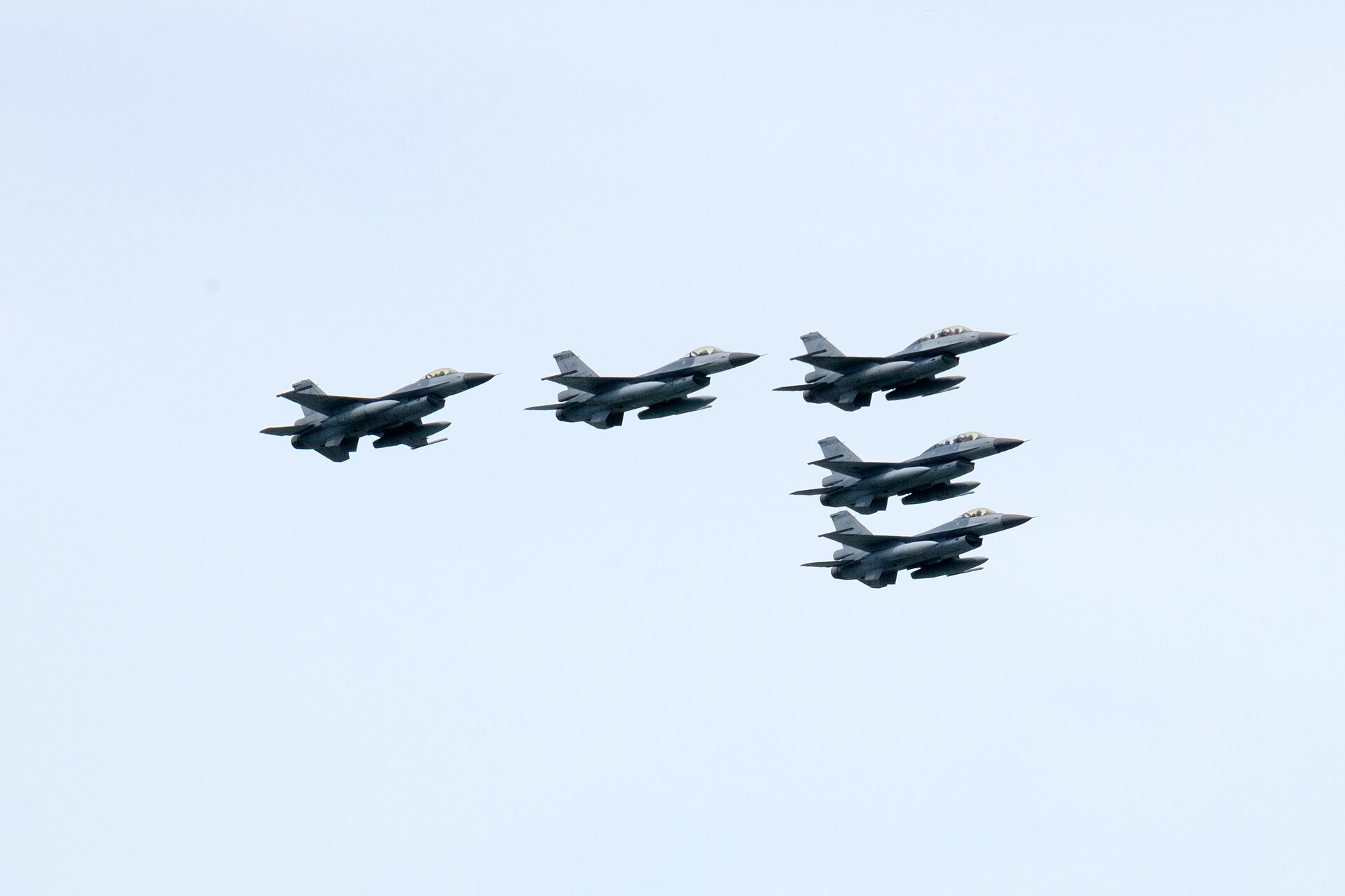 淺藍色天空中,五架中華民國空軍 F-16A/B 戰機排成編隊飛過,左邊三架一字排開,右邊兩架上下錯開