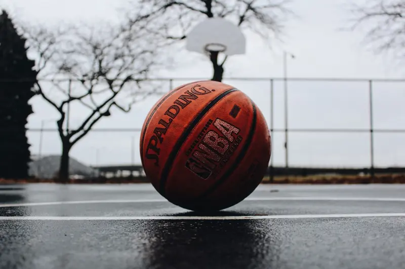 一顆 Spalding 籃球放在雨後的室外球場上