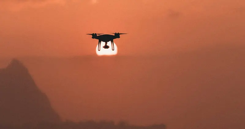 無人機黑色剪影在橙紅色夕陽天空中懸停