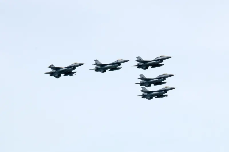 淺藍色天空中，五架中華民國空軍 F-16A/B 戰機排成編隊飛過，左邊三架一字排開，右邊兩架上下錯開