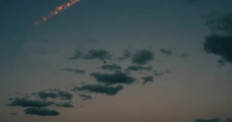 暮色天空中一道明亮的火光軌跡劃過雲層