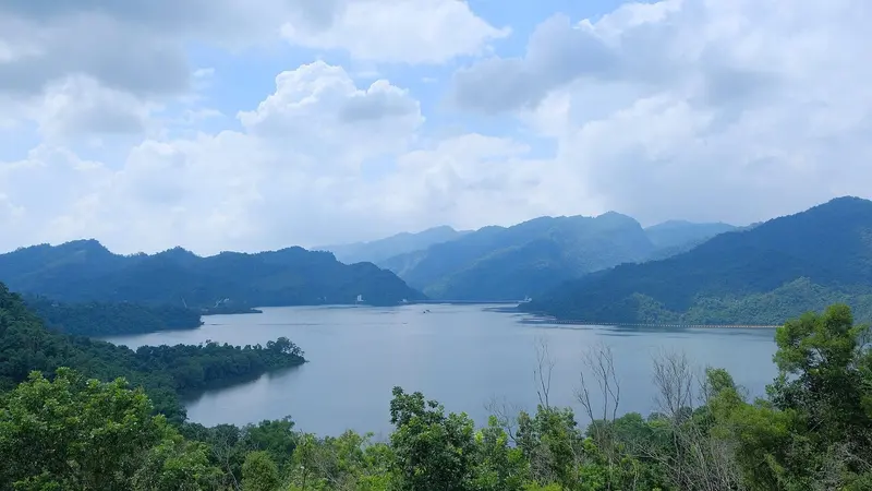 曾文水庫全景，水面在群山之間展開，遠處可以看到壩體與水面上的攔汙索